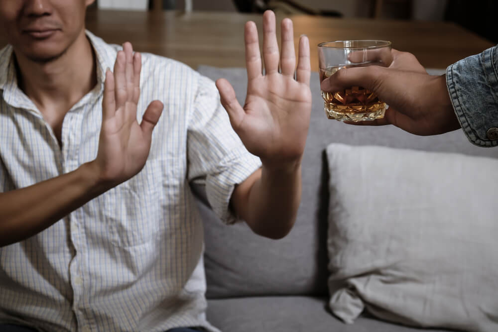 A person turning down a glass of alcohol.