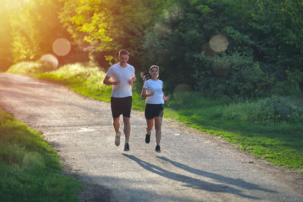 A man and a woman running on a country road.