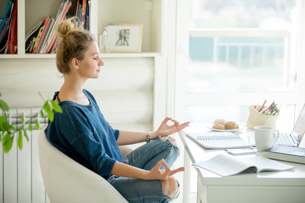 A person meditating at her desk.