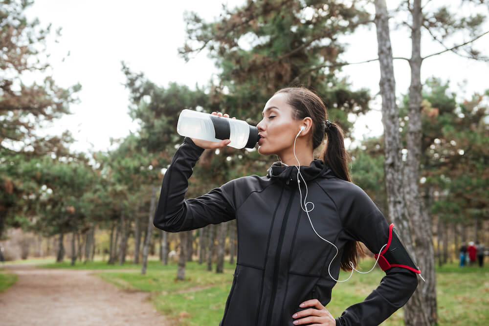 A woman drinking from a water bottle.