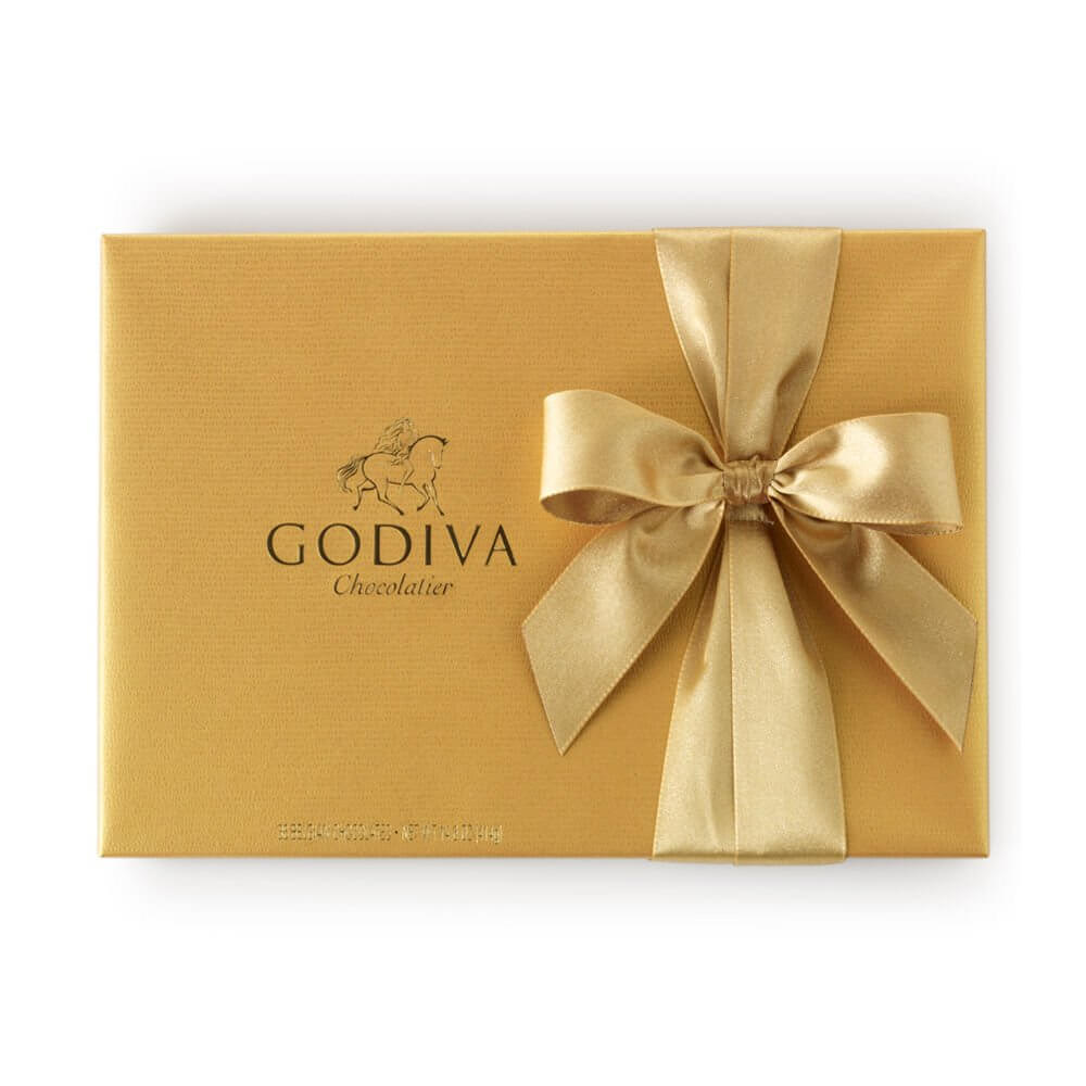 A gold box with a gold ribbon with Godiva chocolate inside.