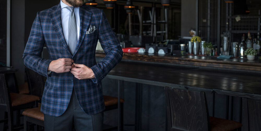 A man wearing a custom plaid suit in a nice bar.