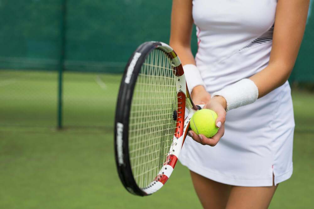 A woman holding a tennis ball and racket.