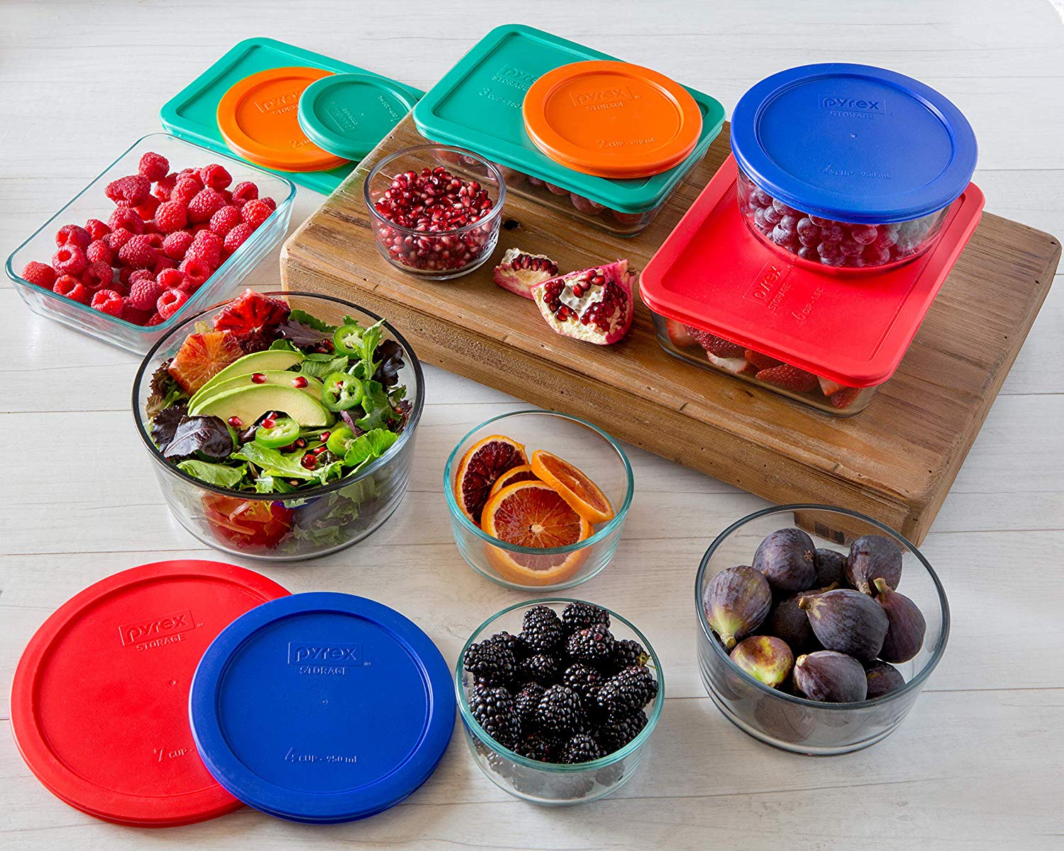A large set of Pyrex containers filled with fruit.