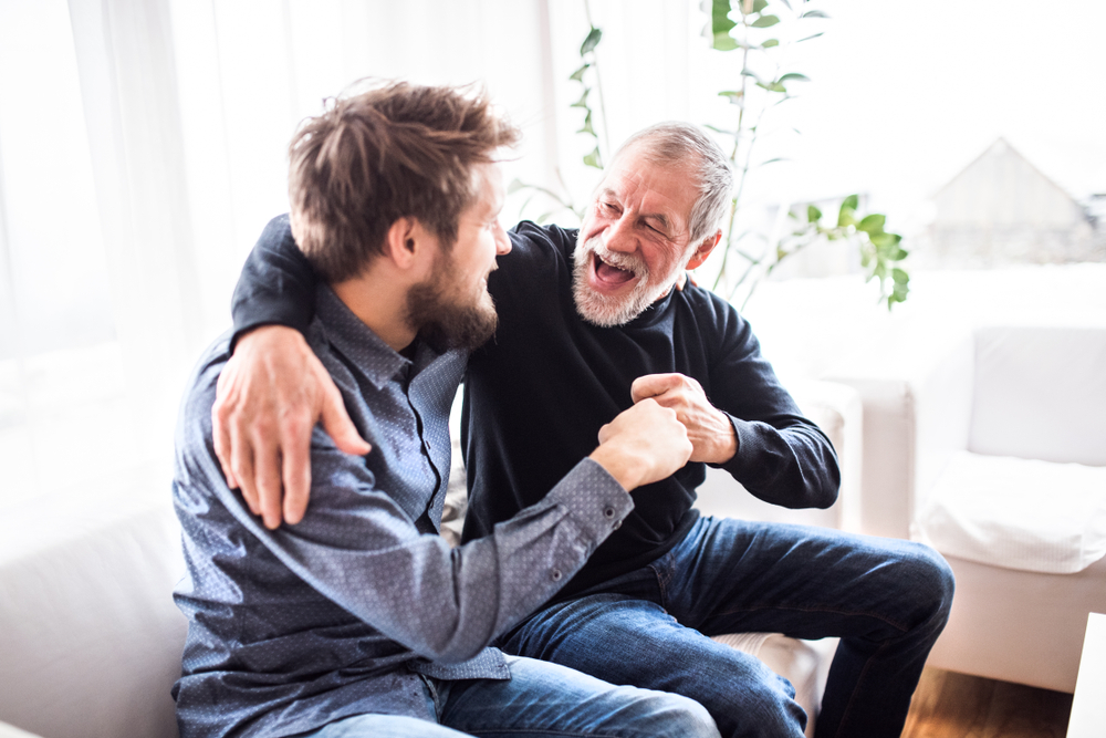 A senior citizen and a young man laughing together.