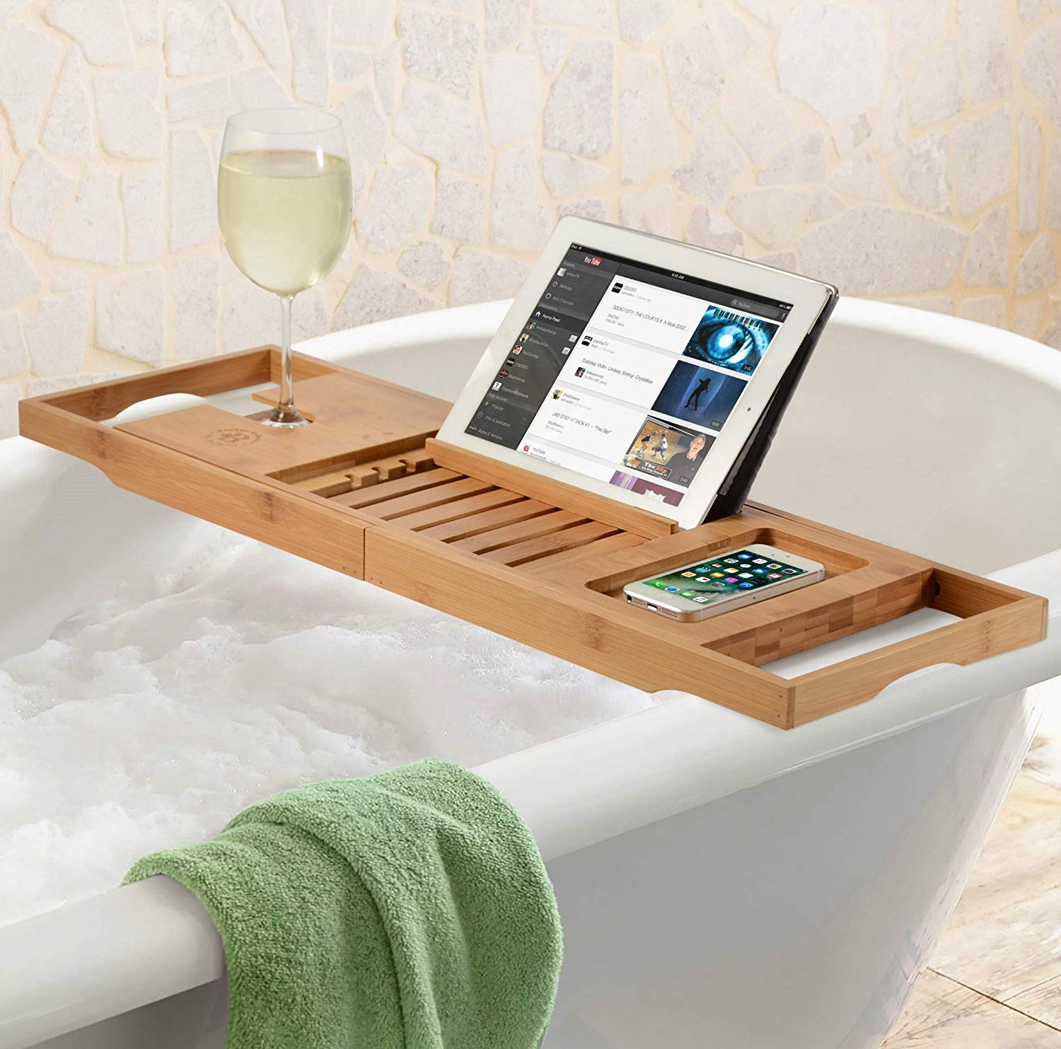 A bamboo bathtub tray over a tub holding an iPad and glass of wine.