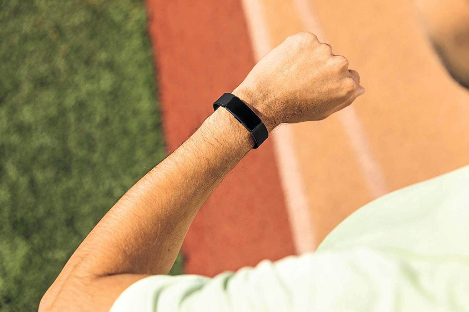 A person on a track looking at their Fitbit Inspire HR.