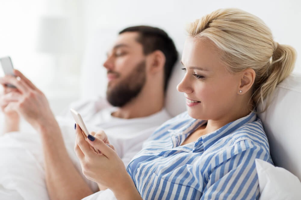 men and woman in bed on their phones