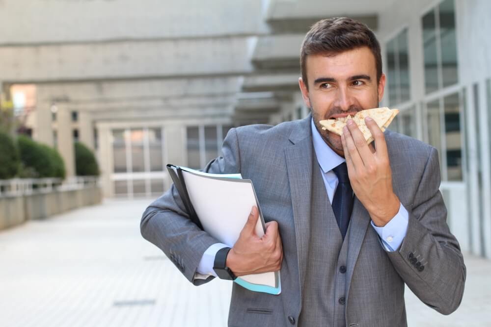 man eating breakfast sandwich on the go