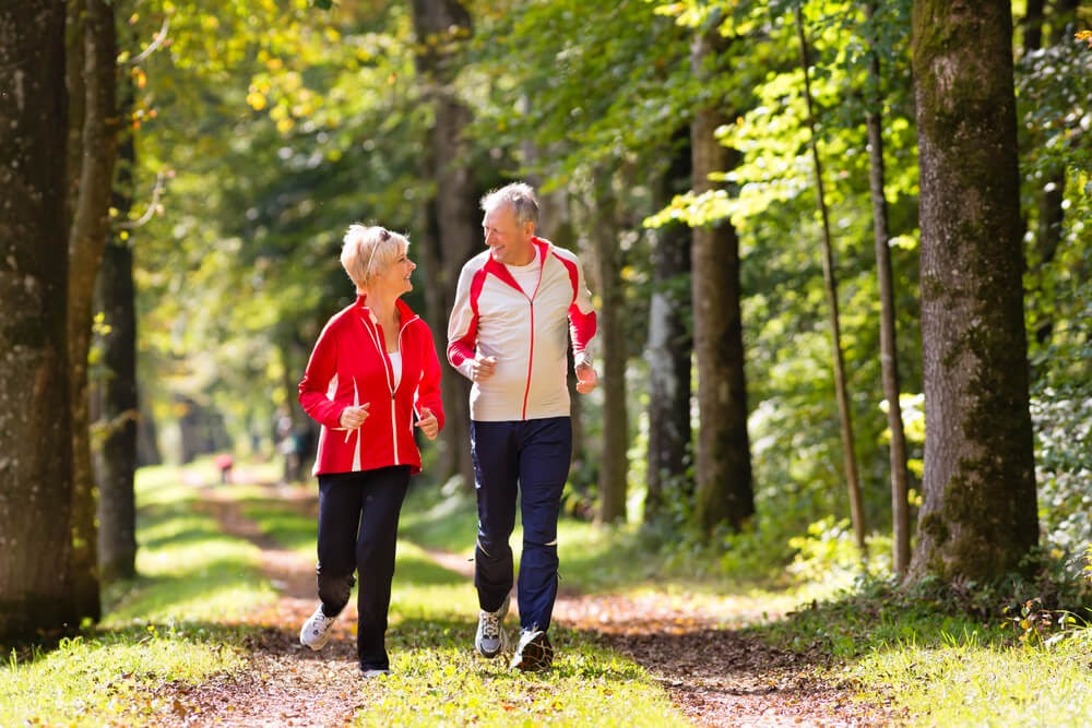 Older couple running on path in woods
