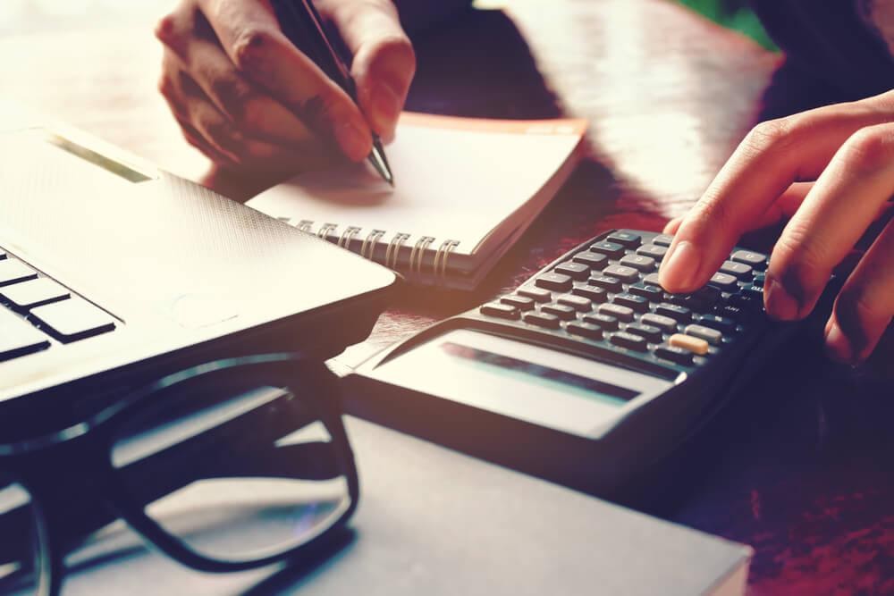 Hands using a calculator and a notepad