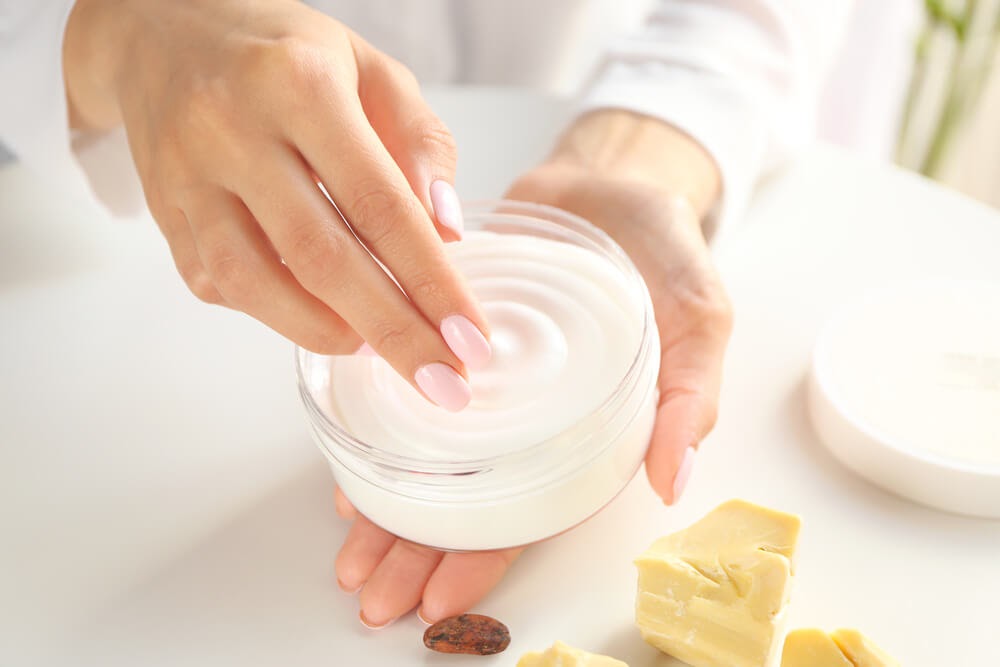 woman with pink nails holding jar of beauty cream