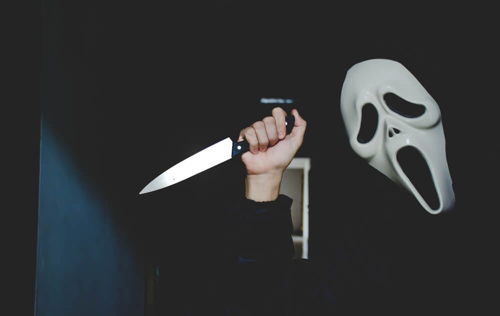 Person wearing scary white mask and holding a knife