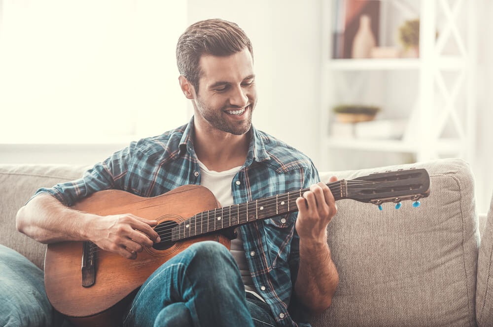 Man smiling and playing the guitar