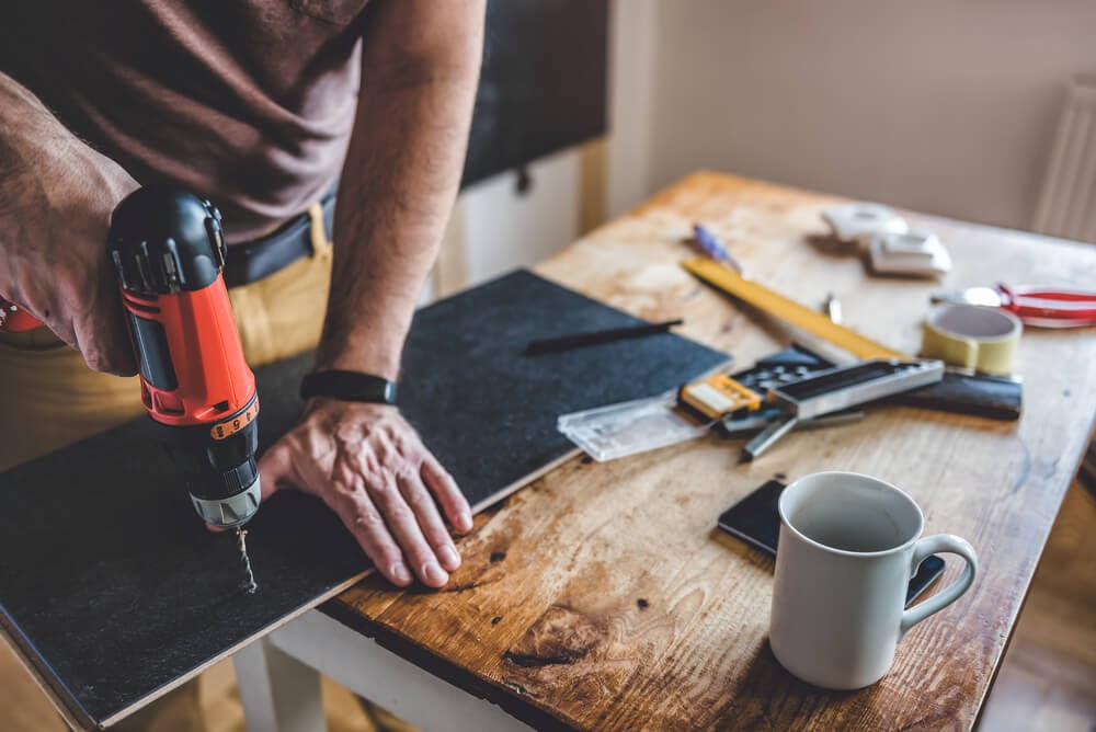 Workbench with tools and person drilling