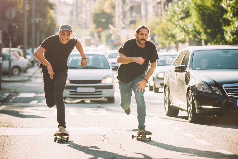 Two people skateboarding in traffic