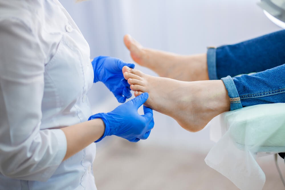 Gloved hands examine feet