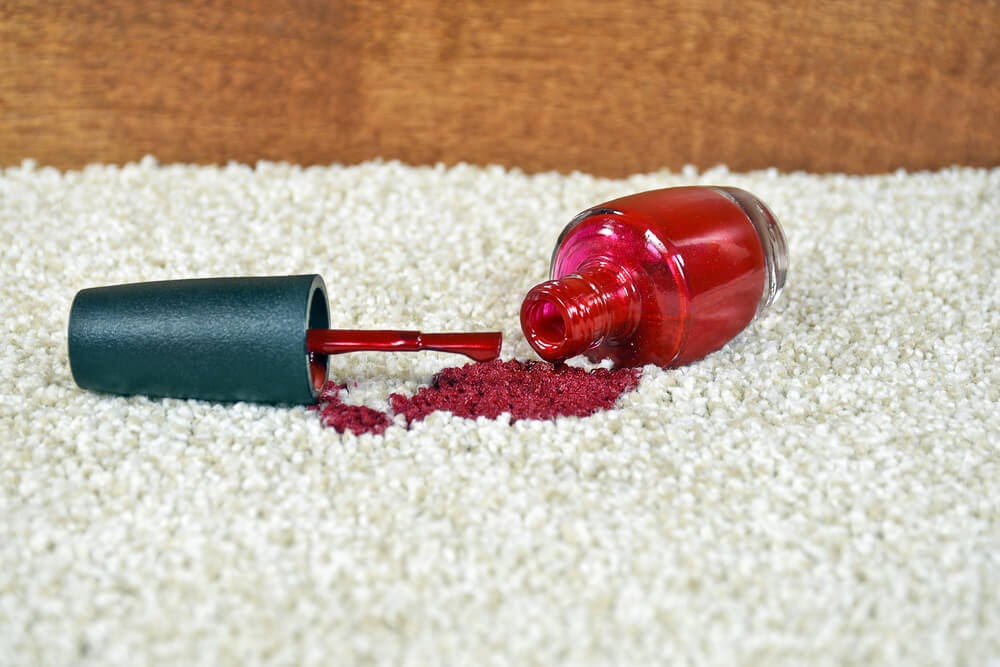 Red nail polish spilled on white rug