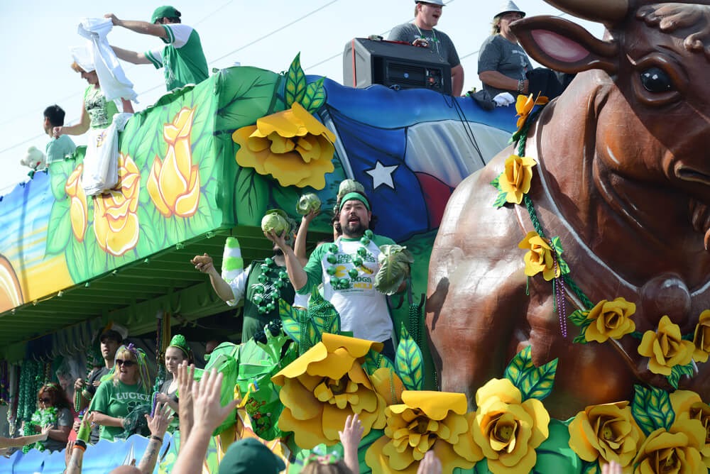Large double decker parade float of a bull, covered in people wearing green