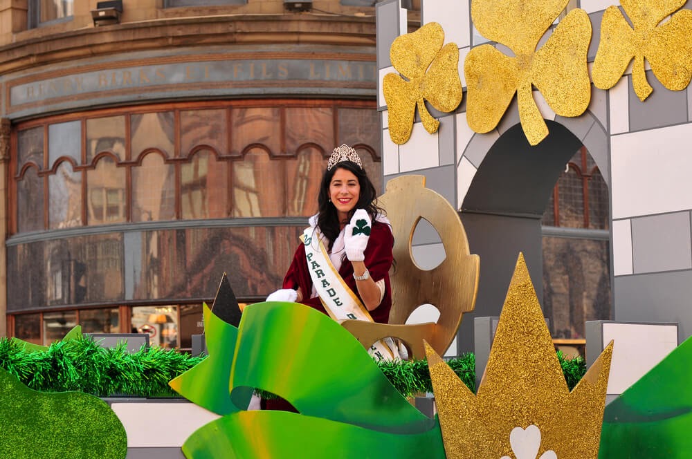 Woman on a shamrock covered parade float wearing a tiara