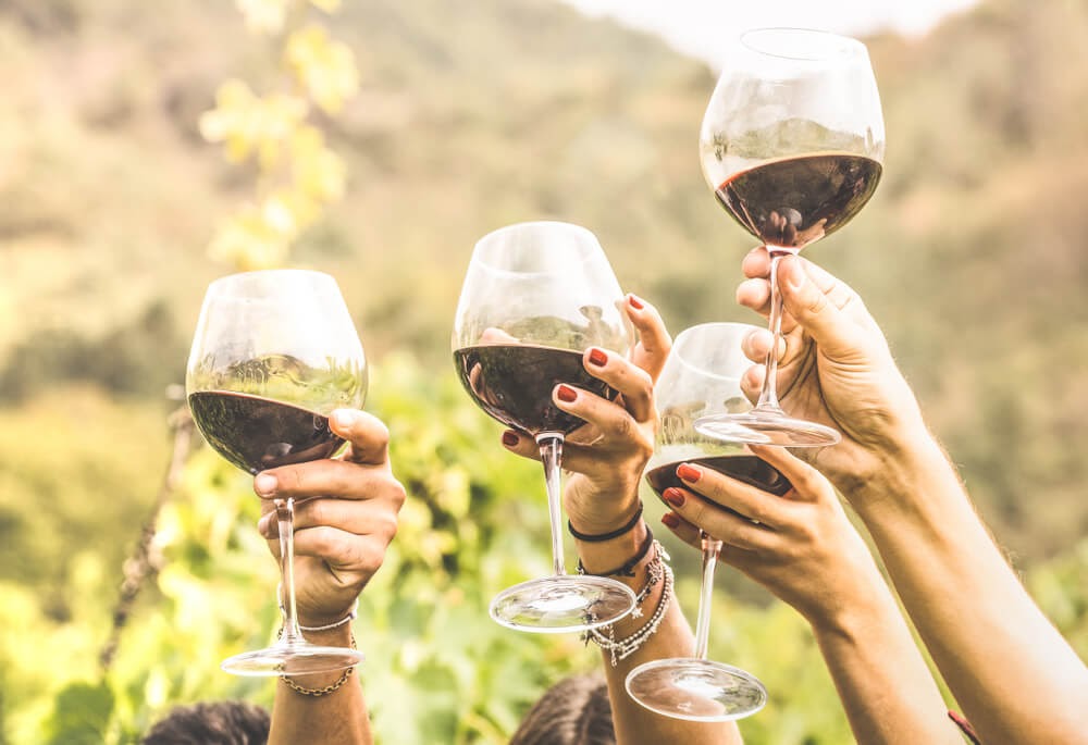 Four wine glasses being held up in the air