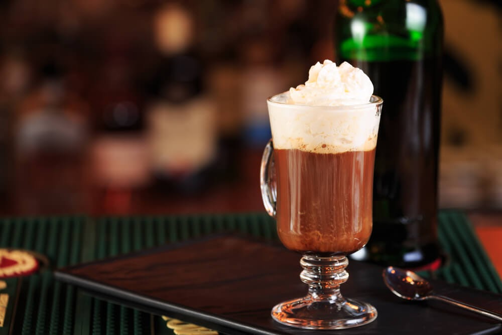 Irish coffee in traditional glass mug with whipped cream on top.