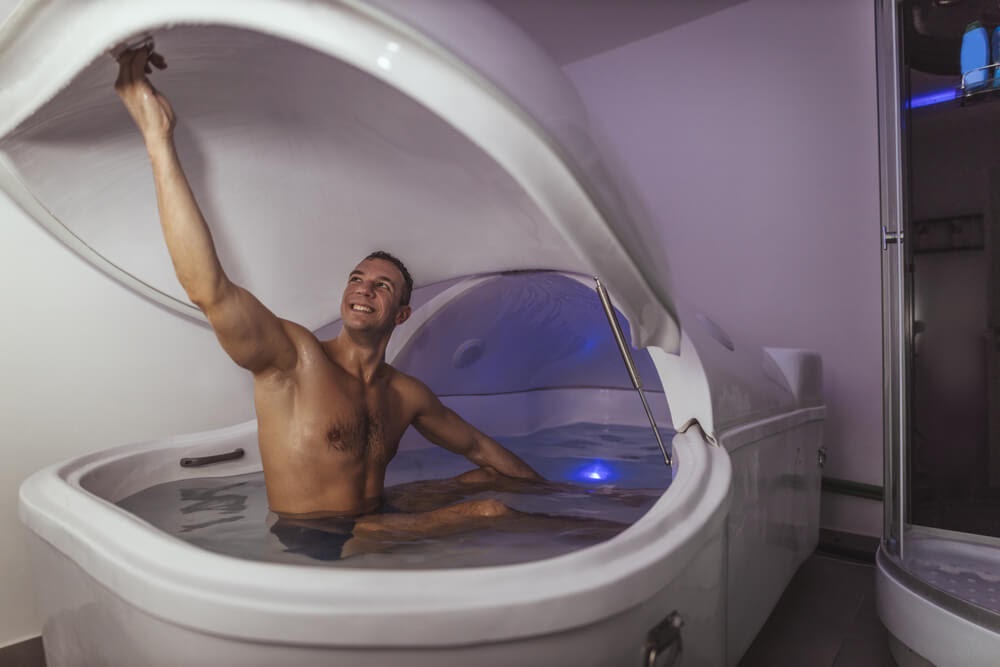 Man smiling while he gets into a floating deprivation tank.