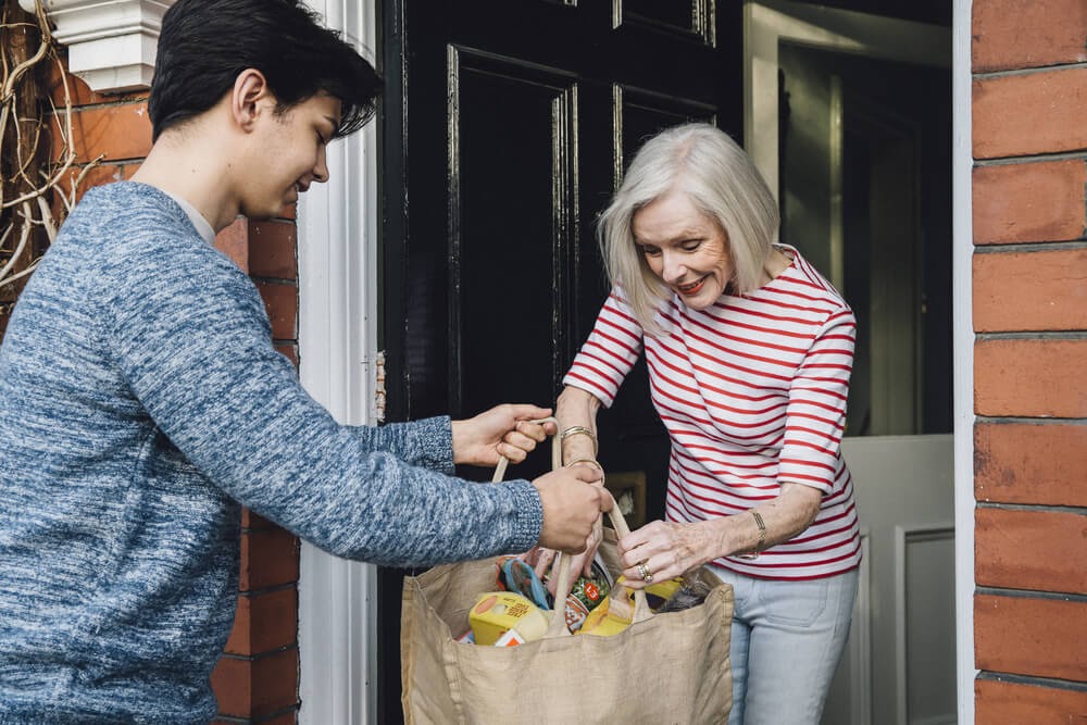 teenage boy delivering groceries to elderly woman