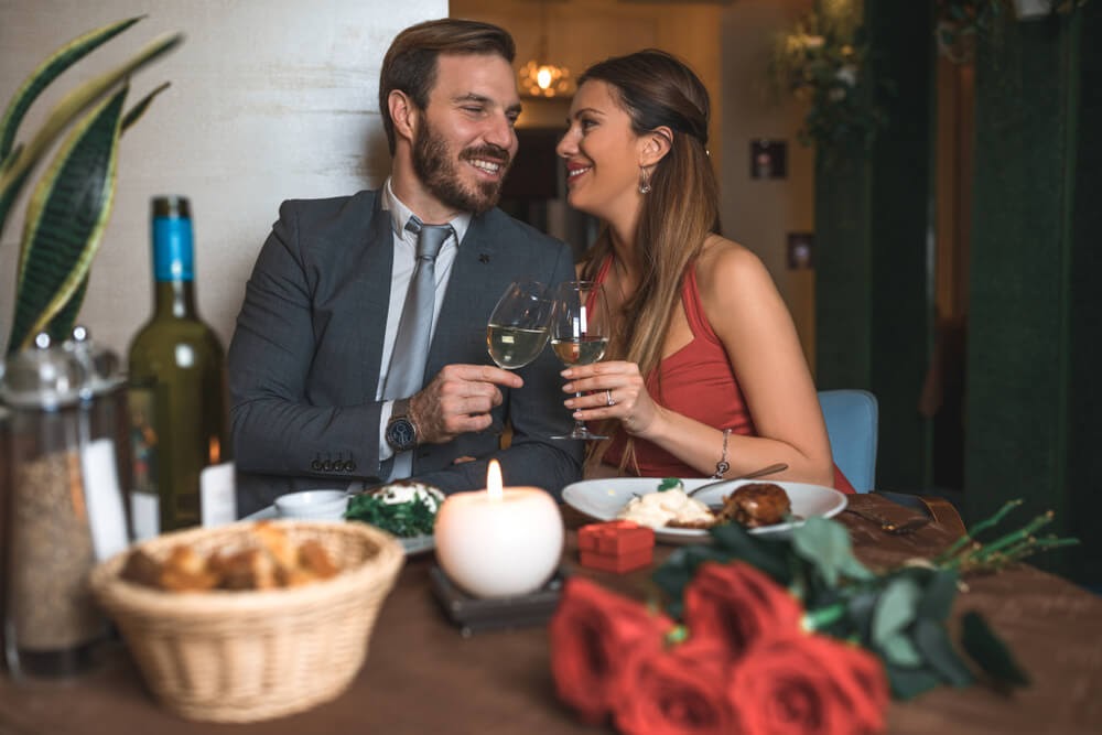 A couple dressed up nicely and toast each other with wine glasses