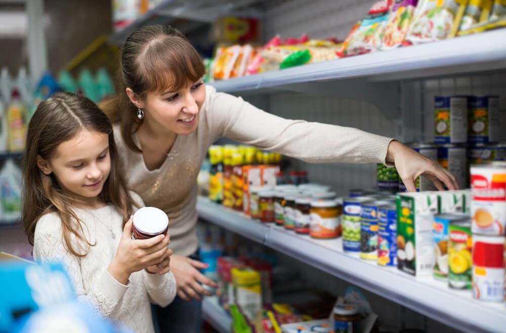 Woman and small child buying canned foods in a store.