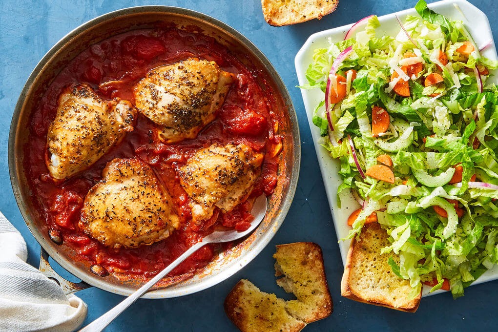 Chicken in red sauce with a salad.
