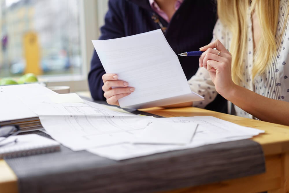 Two people look at paperwork and building plans.