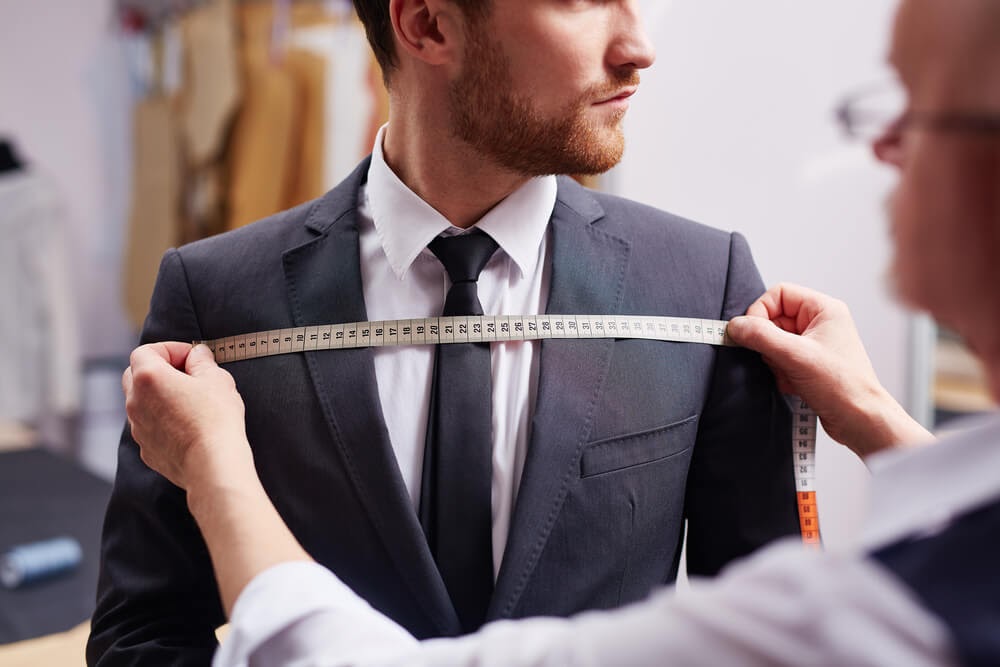 Man in suit being measured across his chest.