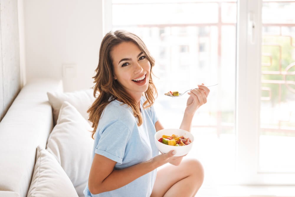 Woman smiling while eating fruit from a bowl