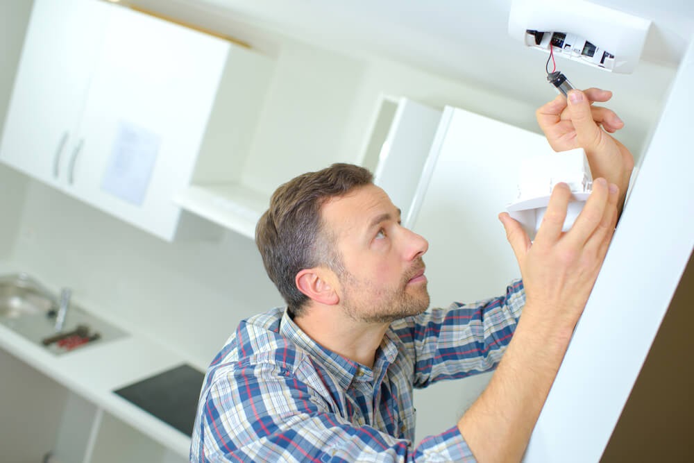 Man changes battery in smoke detector.