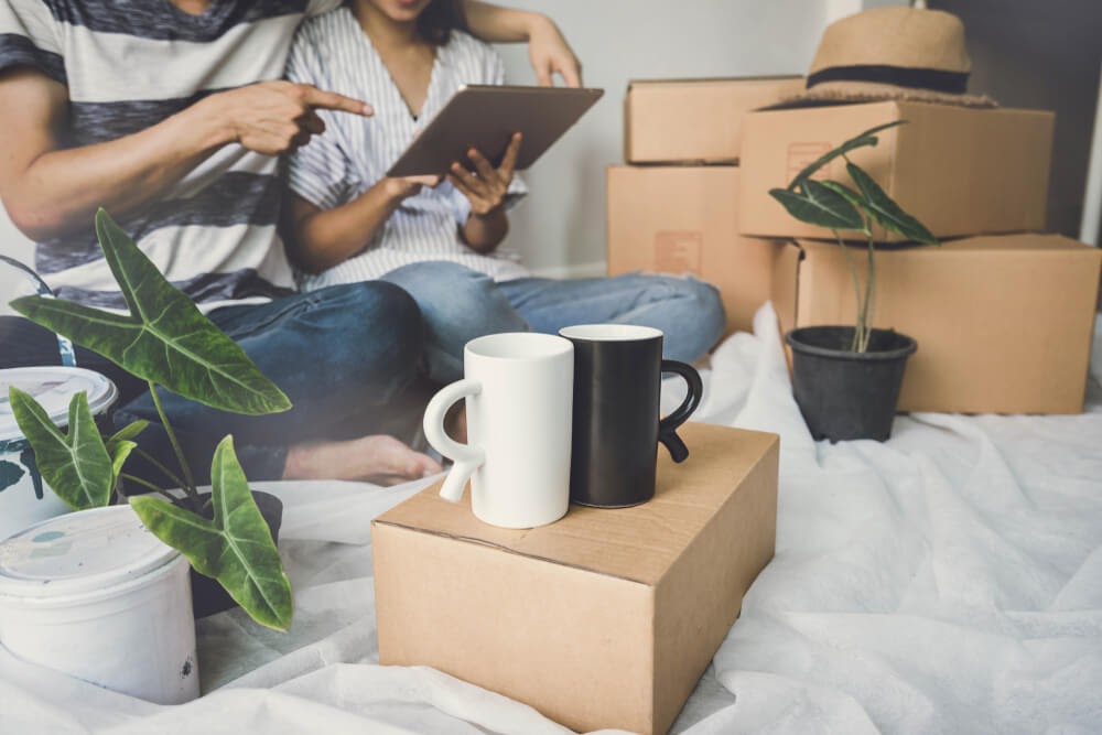 A set of coffee mugs, one black and one white, sit on top of a cardboard box.