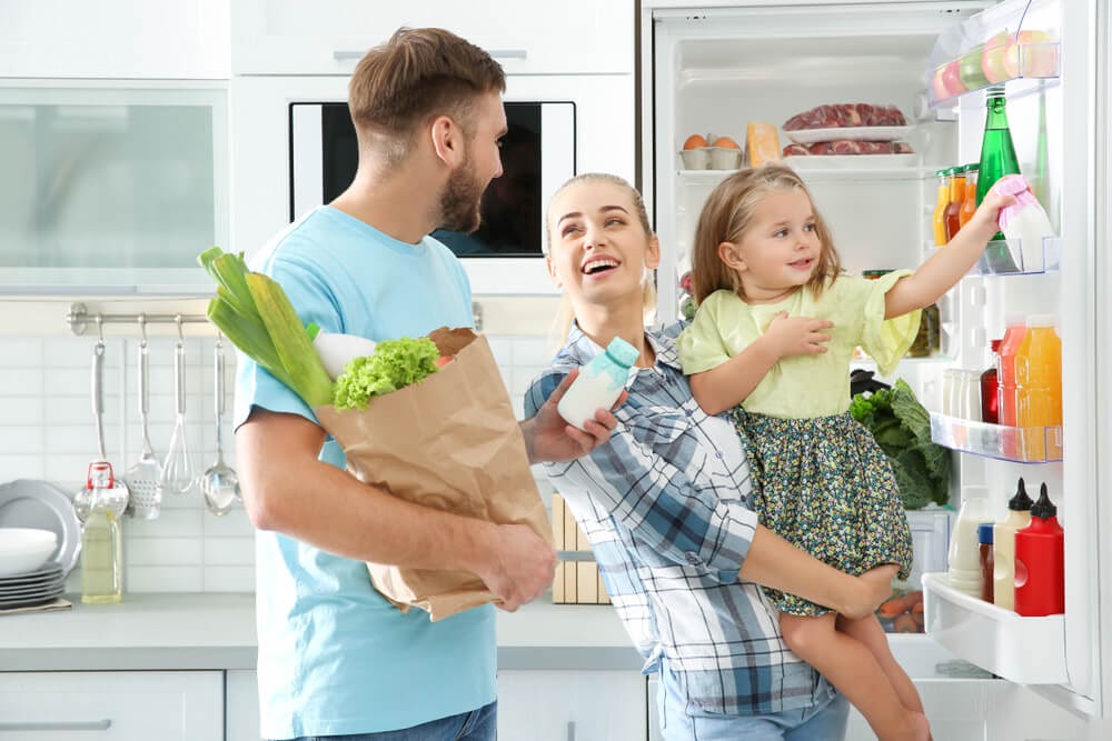 Family putting groceries into the fridge.