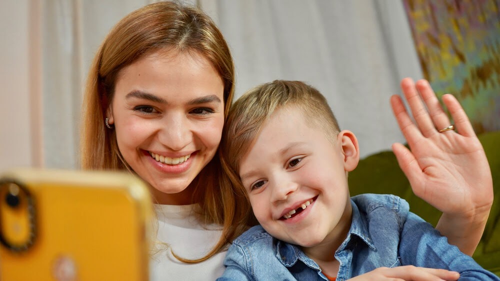 Woman and small child smile at a smartphone.