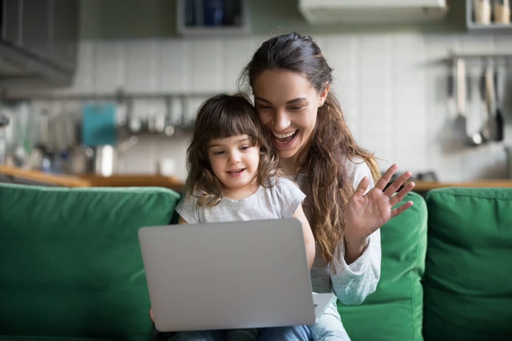 Woman and child smile and wave at their laptop.