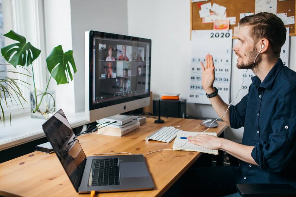 Man speaks to a computer monitor during a virtual meeting.