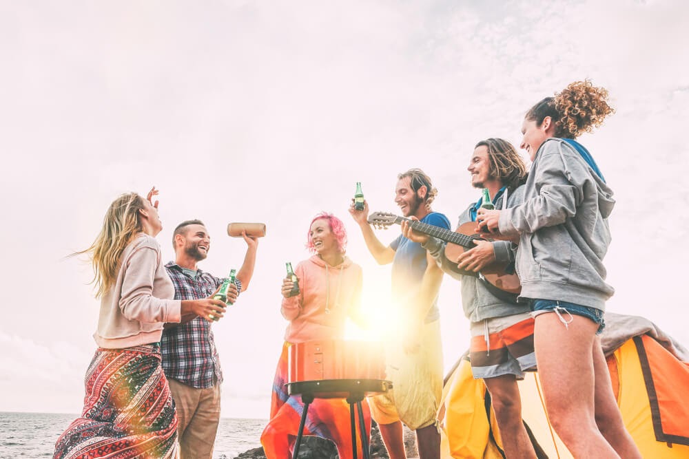 Group of people circle around a small fire pit as the sun goes down.