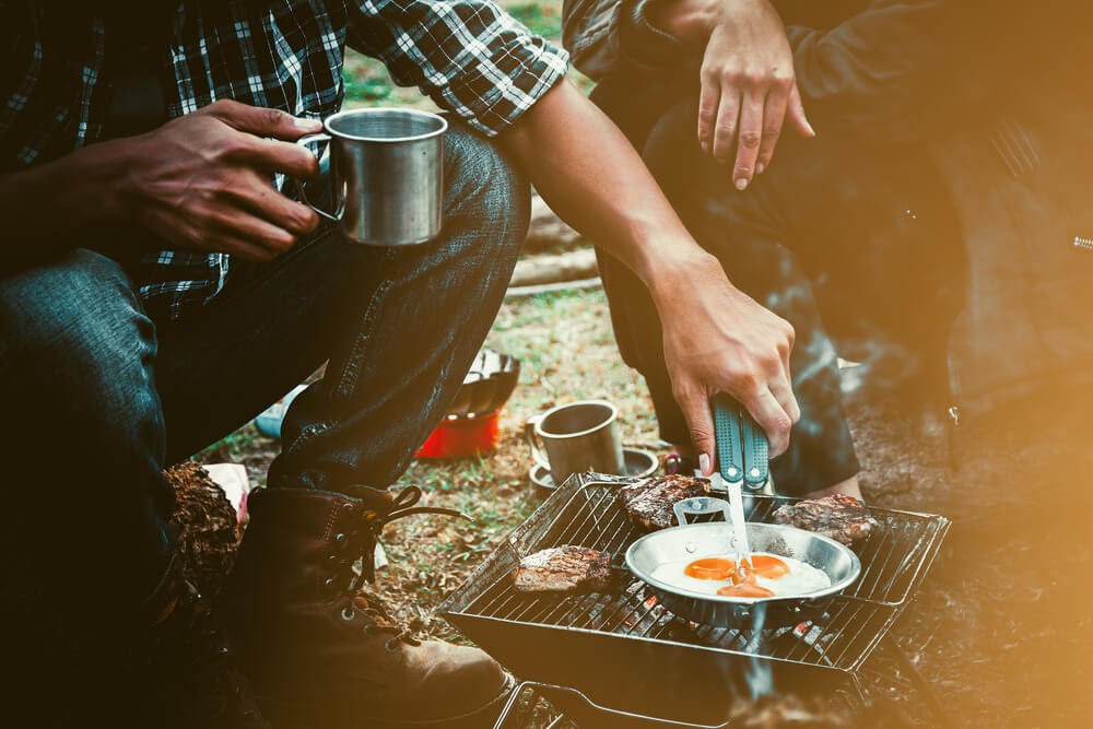 Two people cooking over a camp stove