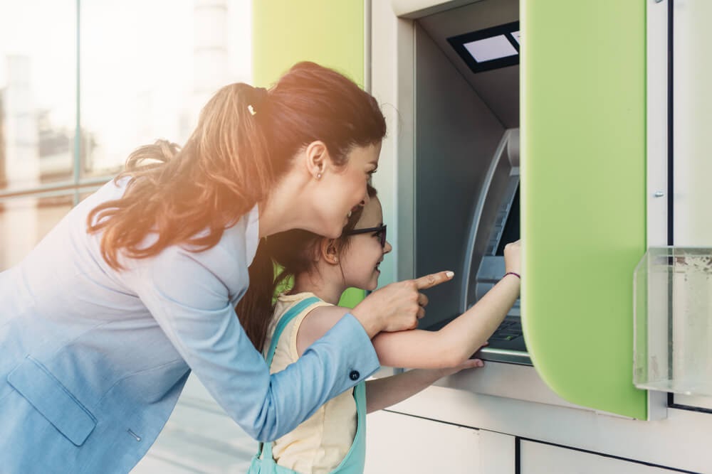 Woman uses ATM with help of young child