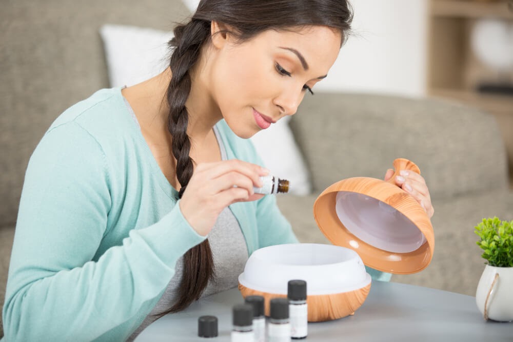 Woman putting oils into a diffuser.