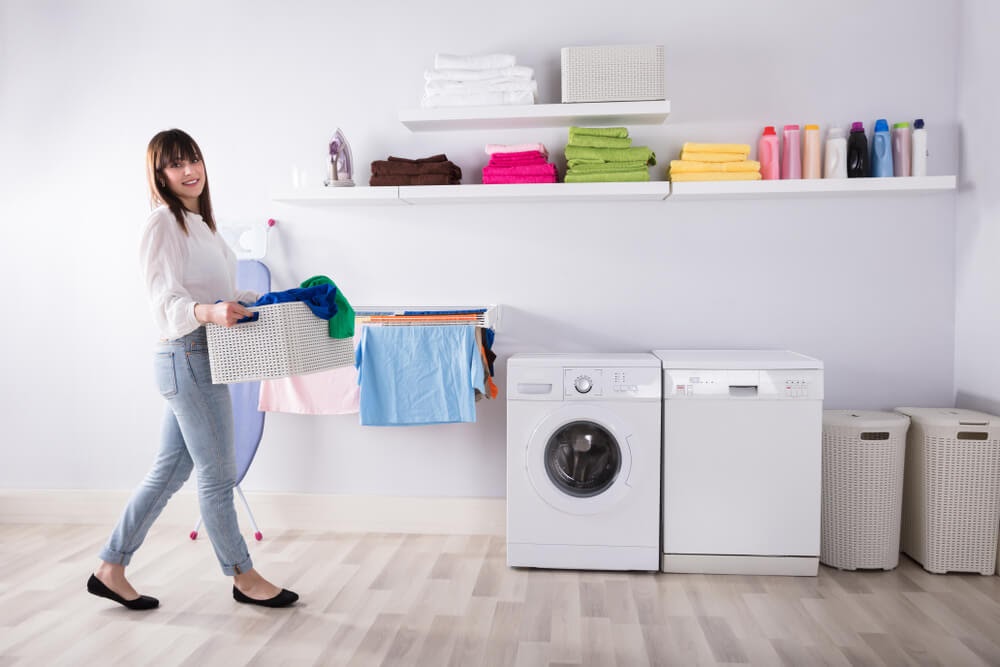 Woman walking to washing maching with a laundry basket.