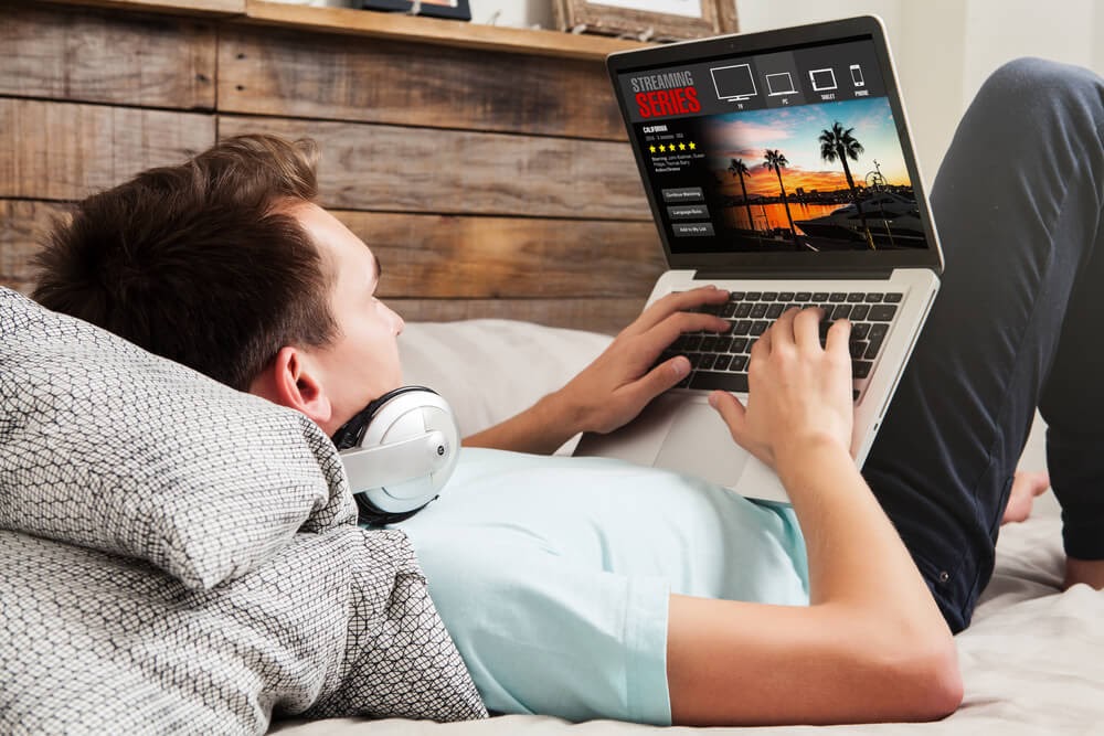 Young man watches TV on laptop