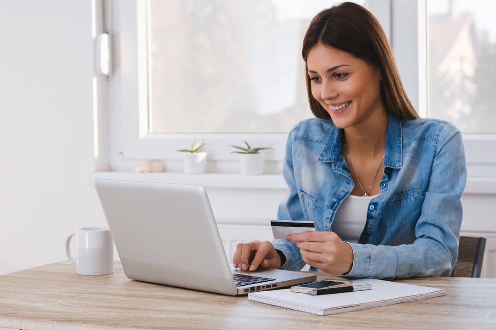 Woman playing with credit card on her laptop.