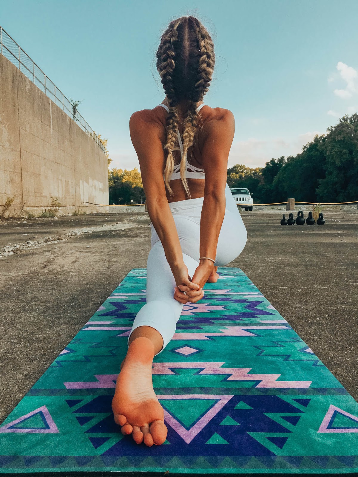 Woman stretching on yoga mat from behind.