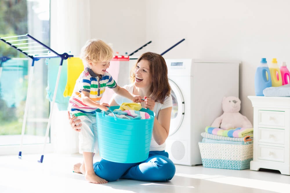 Woman and small child doing laundry in sun-filled room.