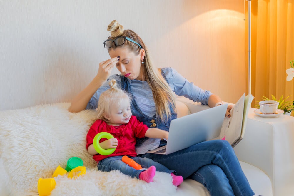 Stressed looking mother sits with small child.
